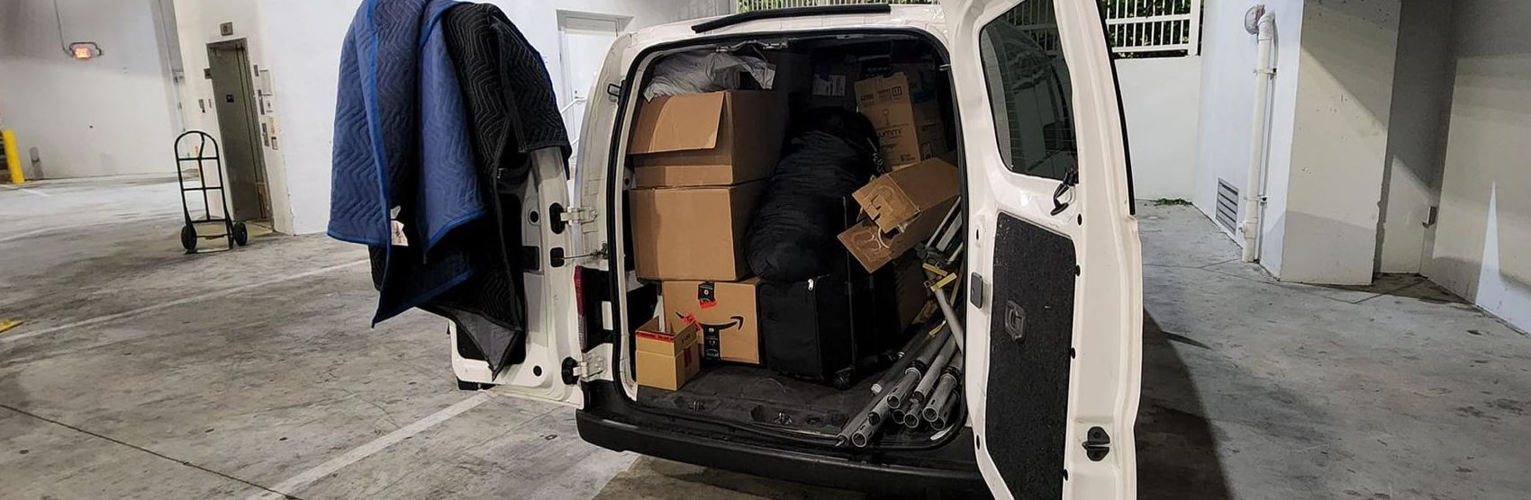 A white van is filled with boxes in a garage.