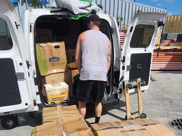 A man is loading boxes into the back of a white van