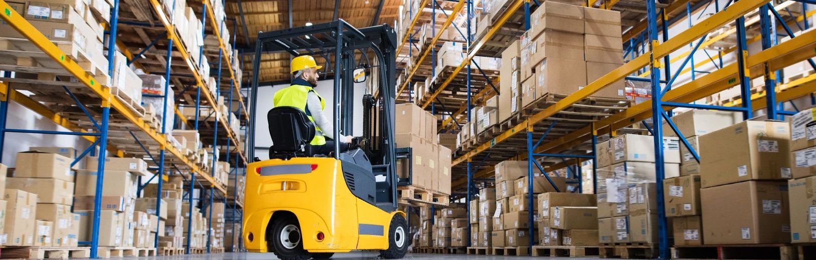 A man is driving a forklift in a large warehouse.