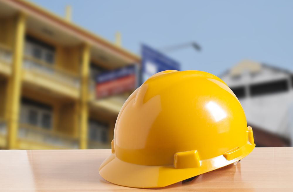 Un casque de sécurité jaune est posé sur une table devant un bâtiment.