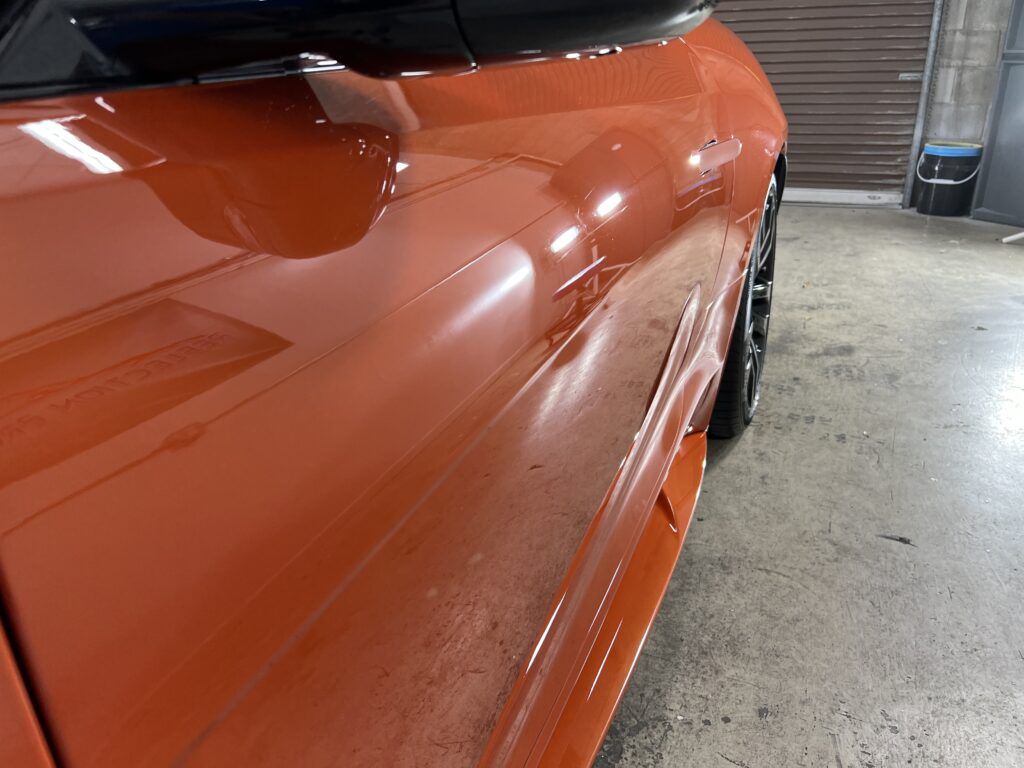 A close up of an orange car parked in a garage.