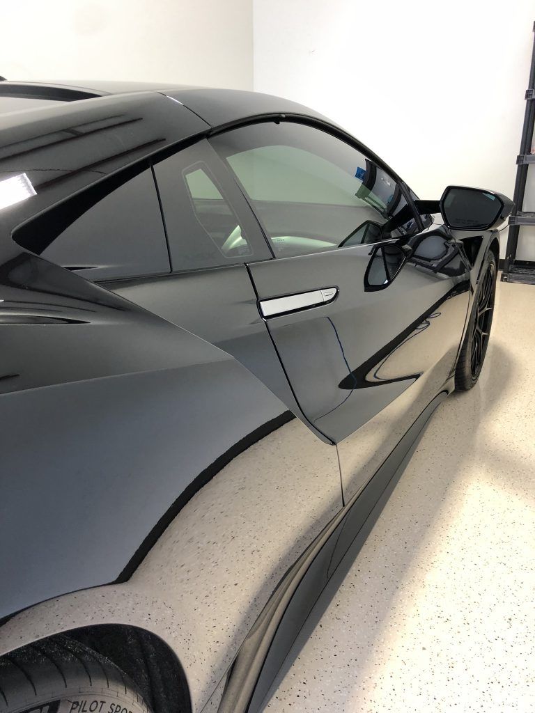 A black sports car is parked in a garage.