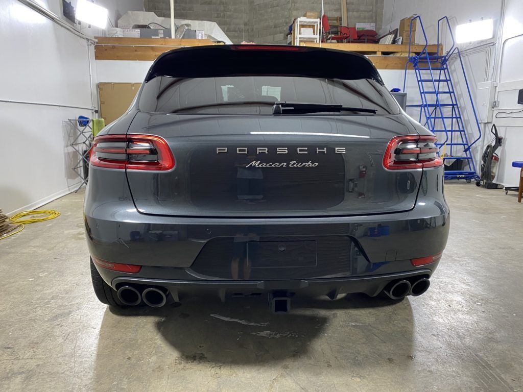 A gray porsche macan turbo is parked in a garage.
