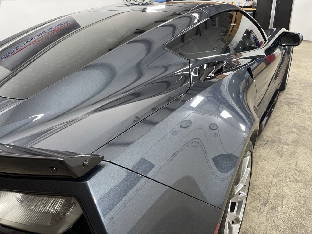 A black sports car is parked in a garage.