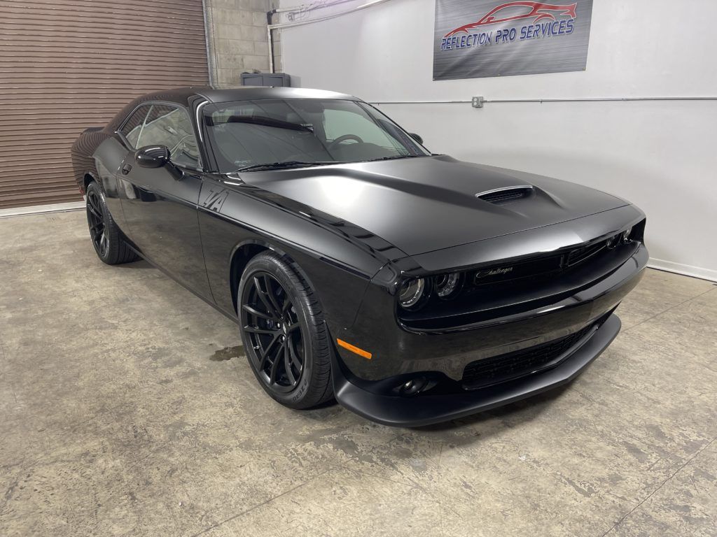 A black dodge challenger is parked in a garage.