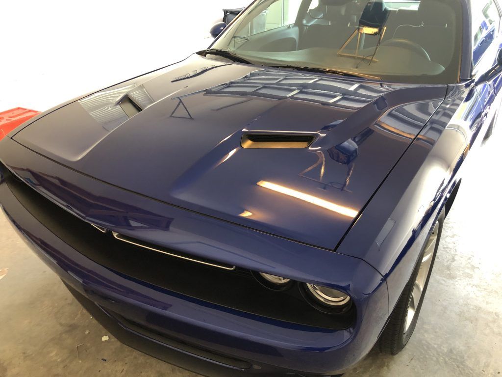 A blue dodge challenger is parked in a garage.