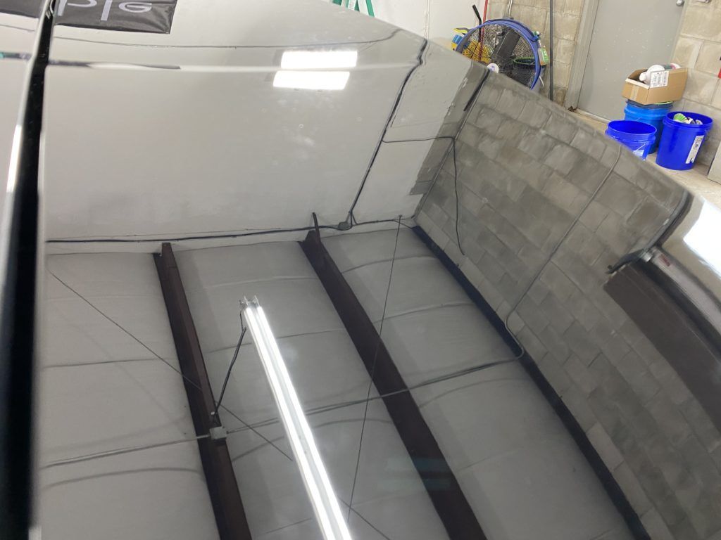 A car is sitting in a garage with a reflection of it in the ceiling.