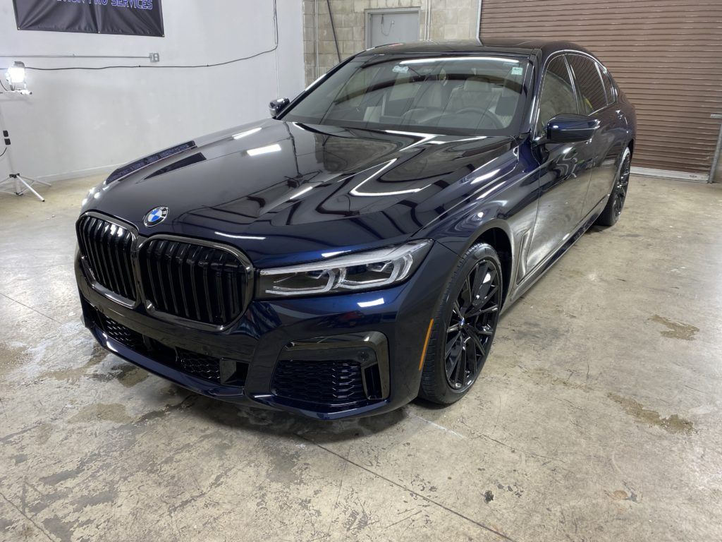 A black bmw 750li is parked in a garage.