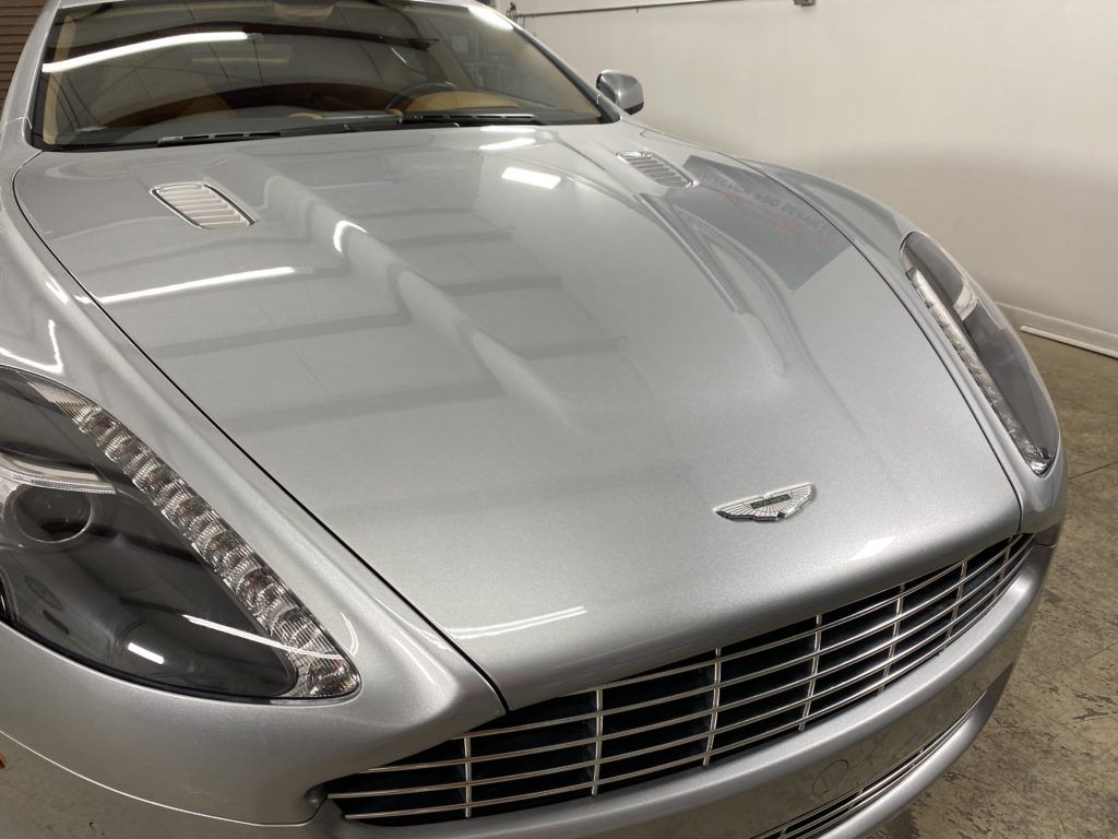 A silver aston martin car is parked in a garage
