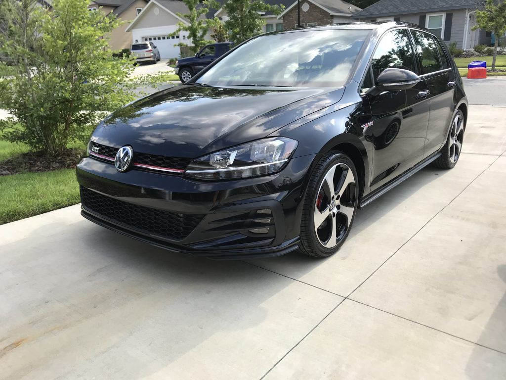 A black volkswagen golf gti is parked in a driveway.