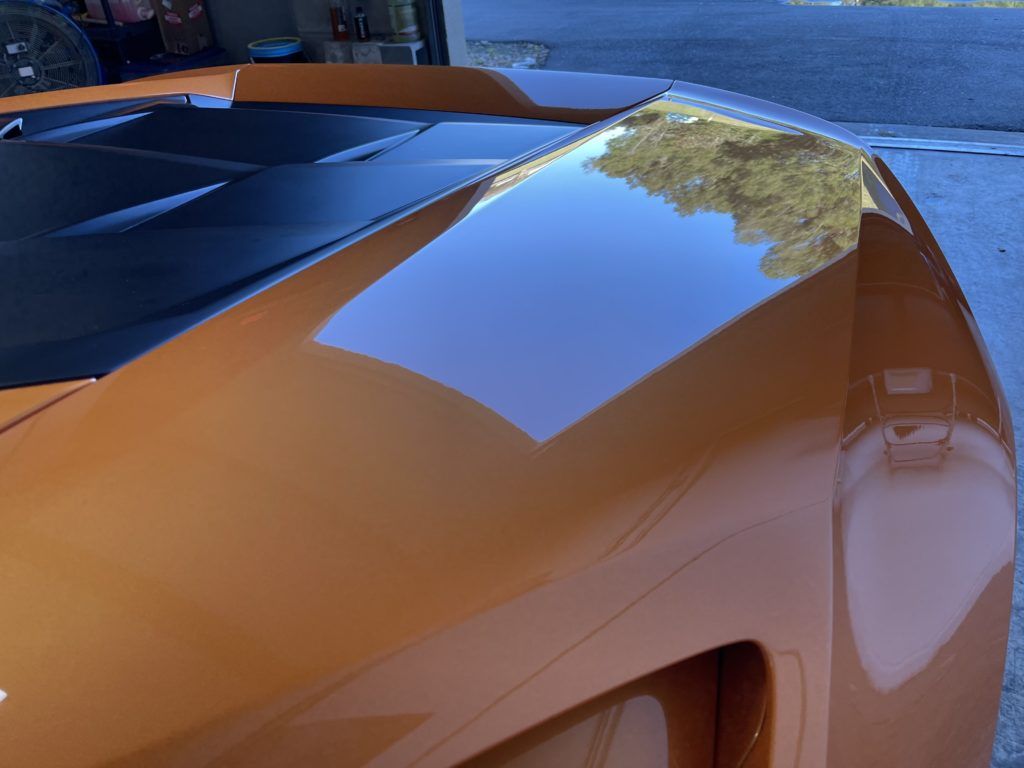 A close up of the hood of an orange sports car