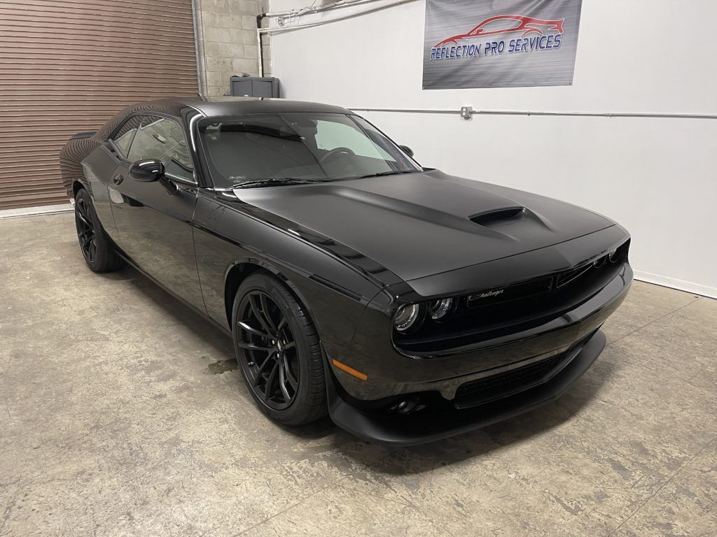 A black dodge challenger is parked in a garage.