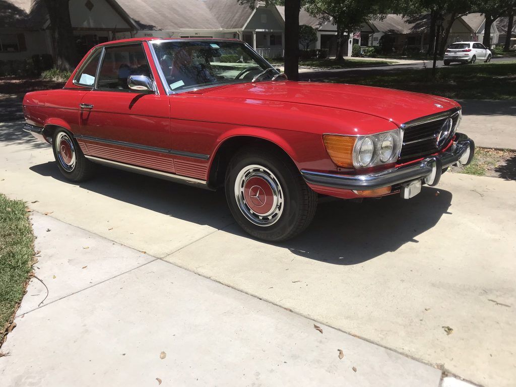 A red car is parked on the side of the road.