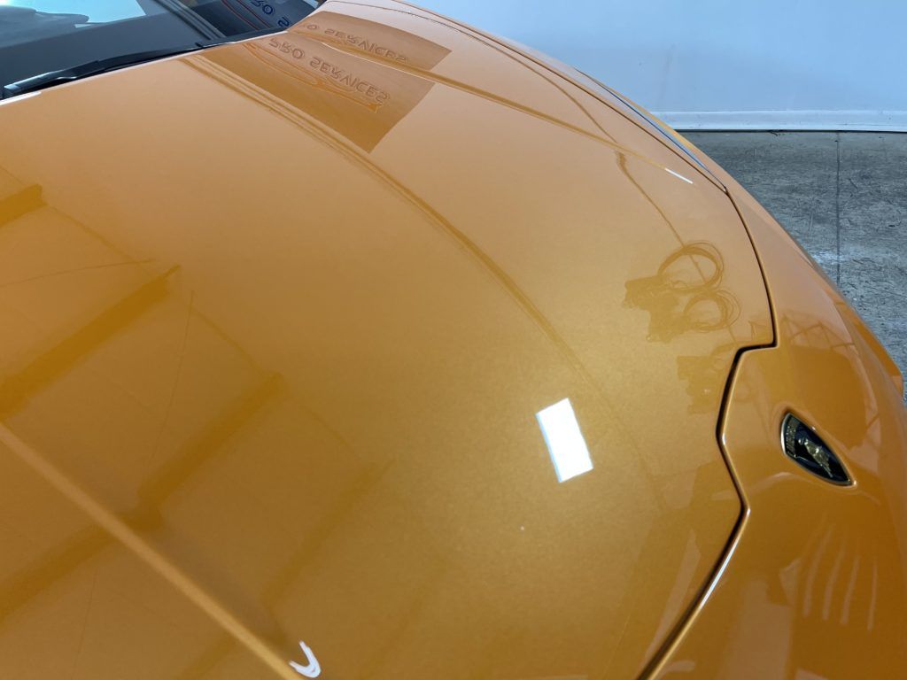 A close up of the hood of an orange car