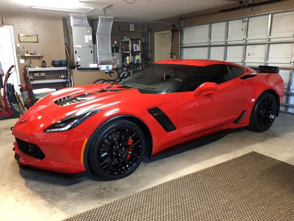 A red sports car is parked in a garage.