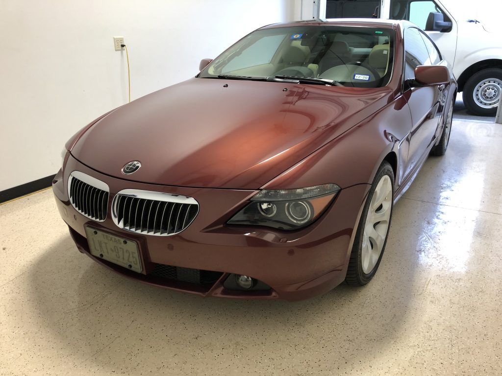 A red bmw is parked in a garage next to a white truck.