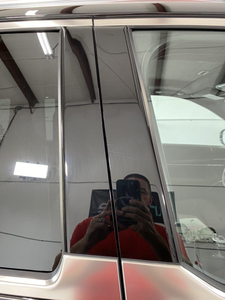 A man is taking a picture of himself in the mirror of a car.