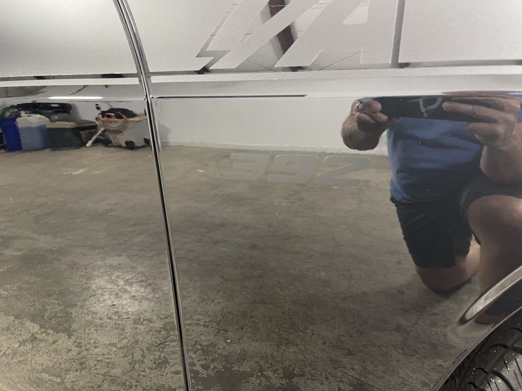 A person is taking a picture of a car in a garage.