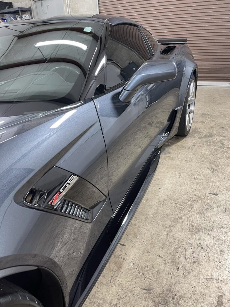 A black sports car is parked in a garage.