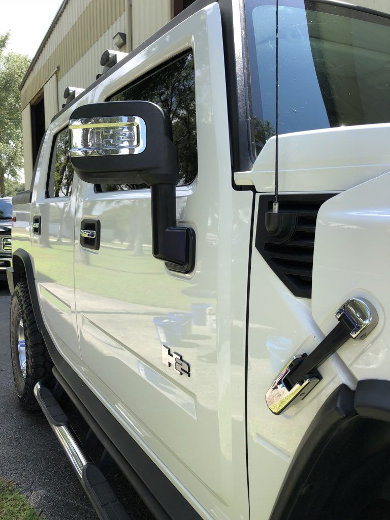 A white hummer h2 is parked in front of a building.