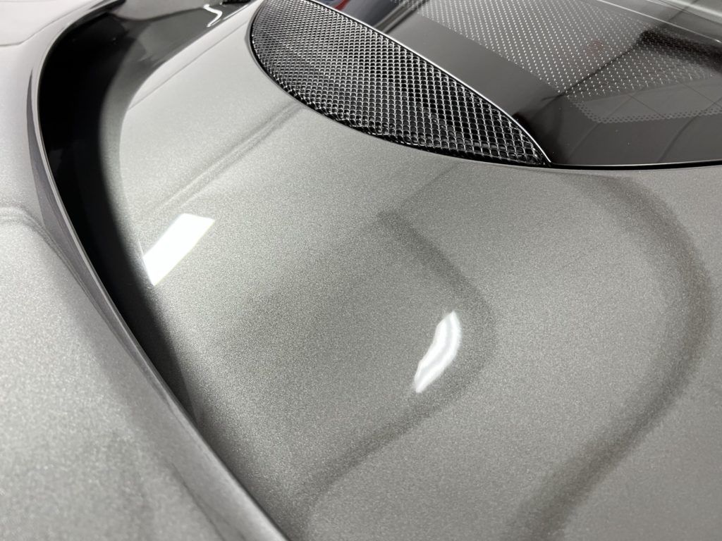 A close up of the hood of a silver car.