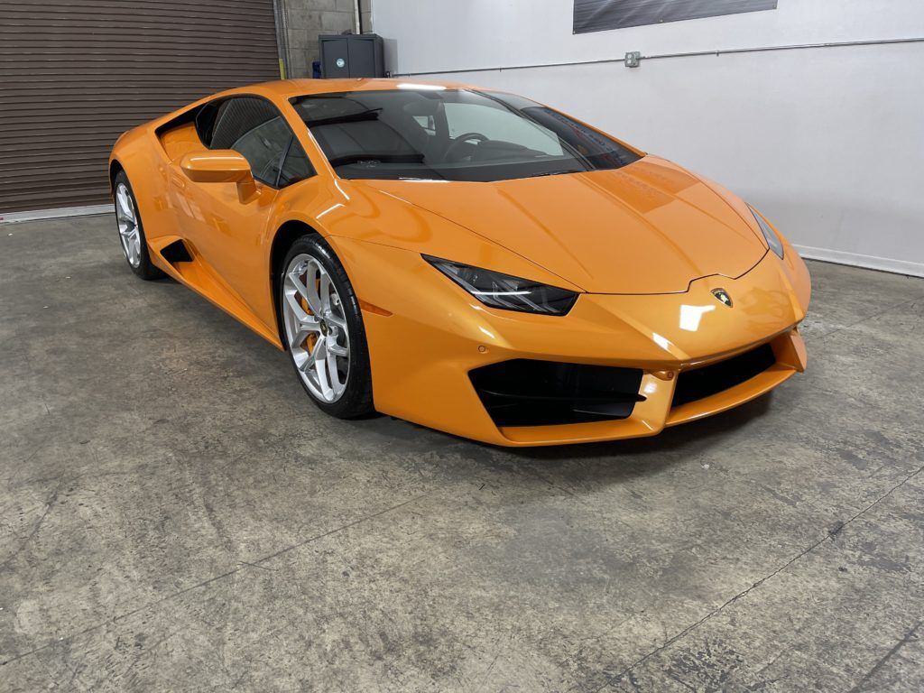 An orange lamborghini huracan is parked in a garage.