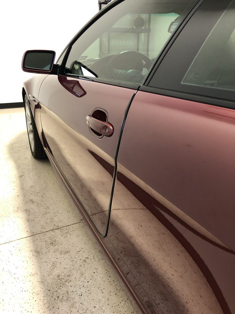 A red car is parked in a garage with the door open