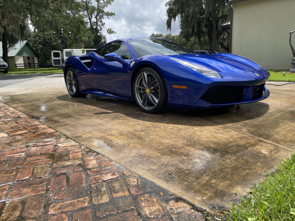 A blue ferrari 488 gtb is parked in a driveway.