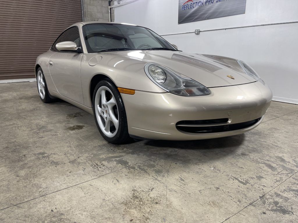 A gold porsche 911 is parked in a garage.