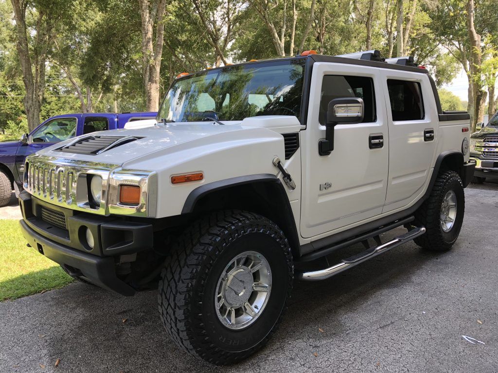 A white hummer h2 is parked in a parking lot.