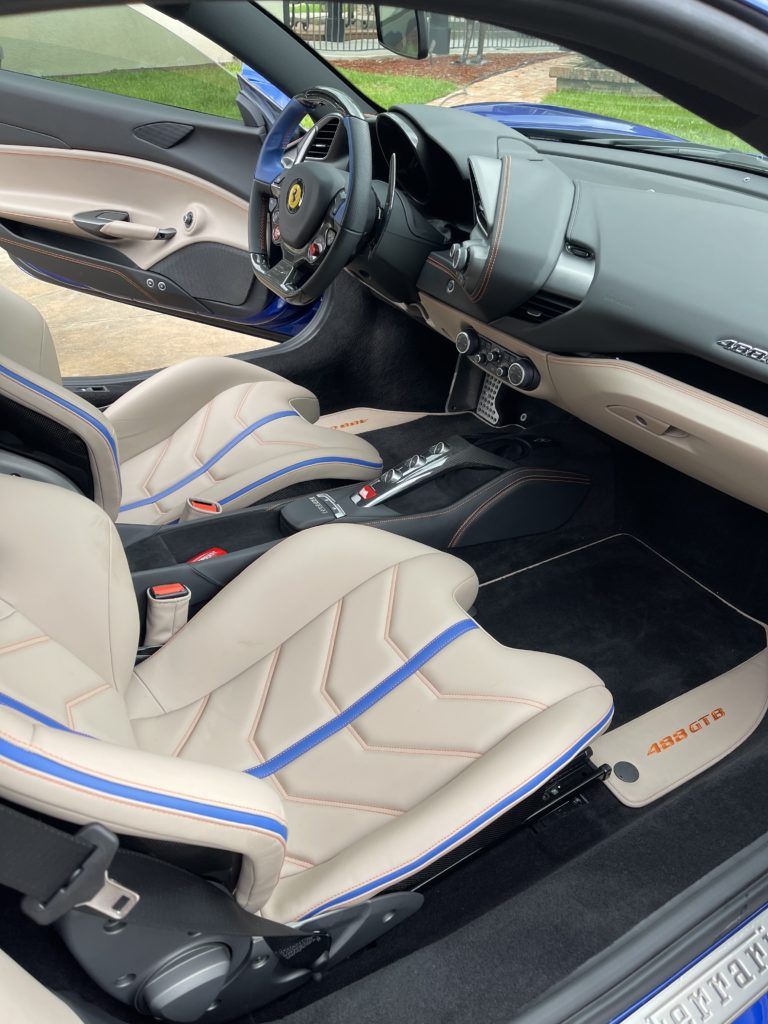 The interior of a ferrari 488 spider with the door open.