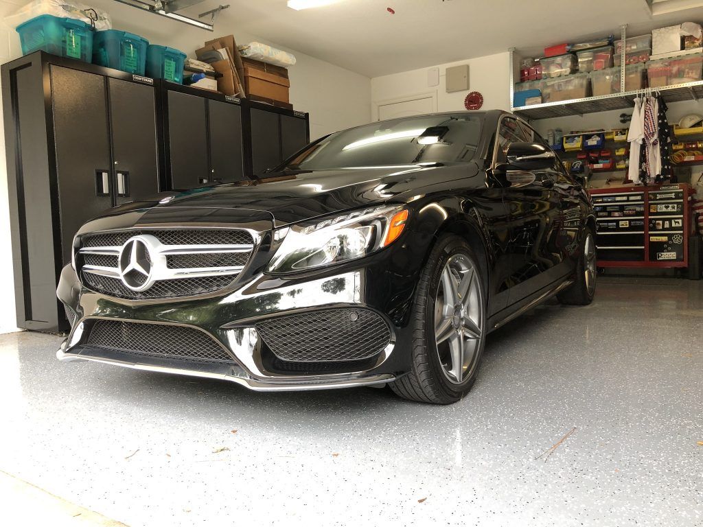 A black mercedes benz is parked in a garage.