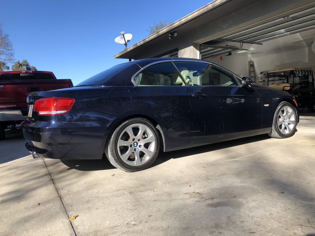A blue car is parked in a driveway in front of a garage.