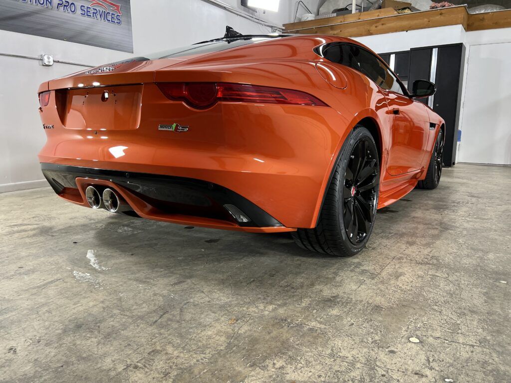 A red jaguar f type is parked in a garage.