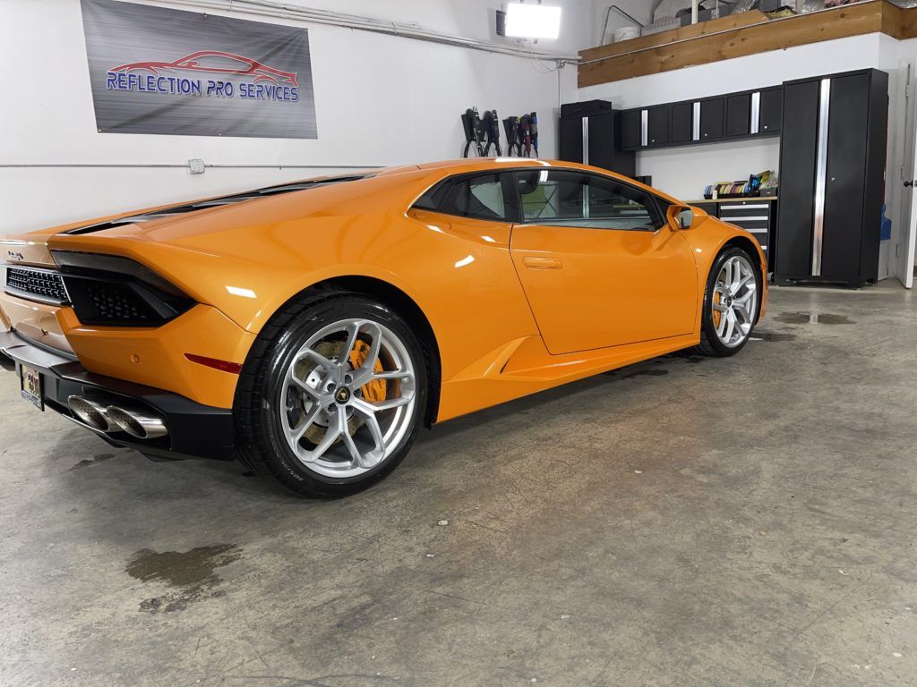 An orange lamborghini huracan is parked in a garage.