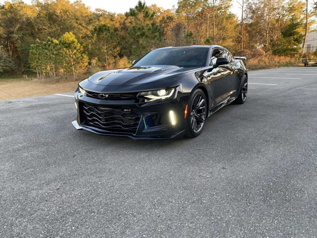 A black chevrolet camaro is parked on the side of the road.