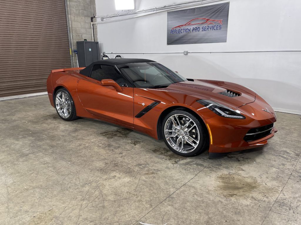 A red corvette convertible is parked in a garage.