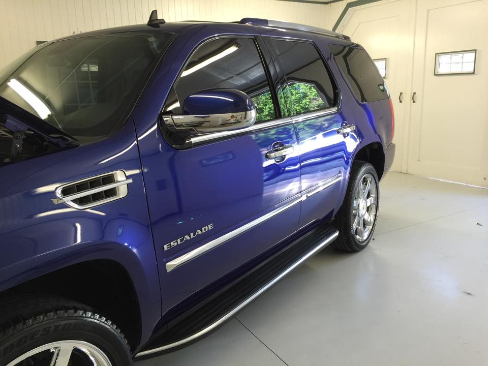 A blue escalade suv is parked in a garage.