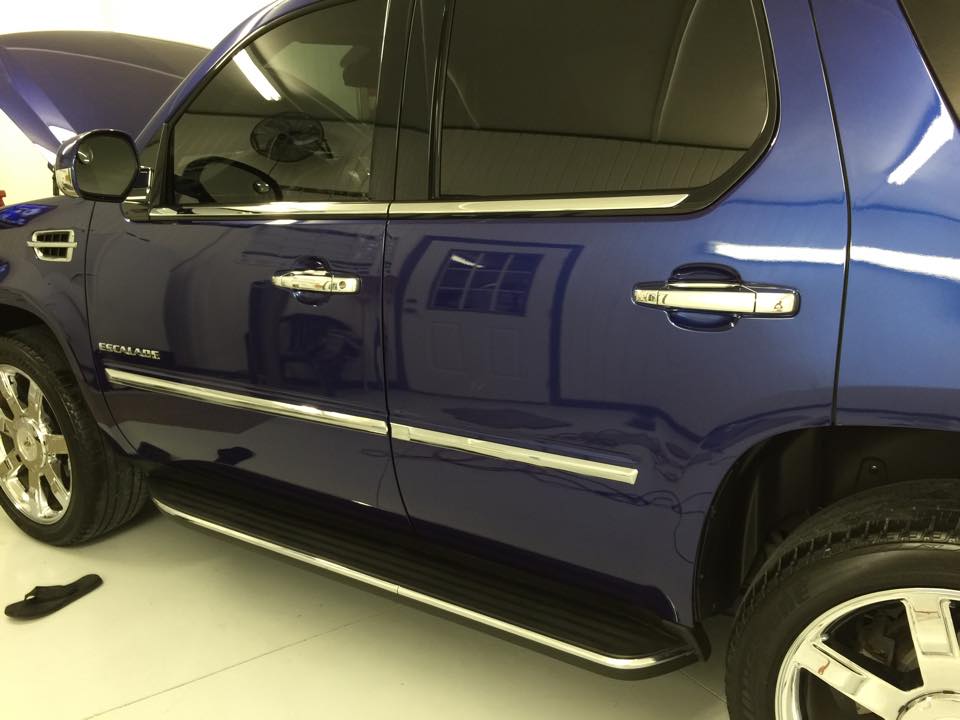 A blue suv is parked in a garage with the hood up