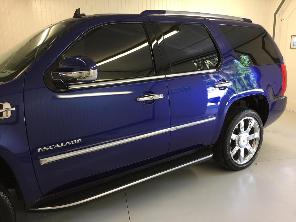 A blue escalade suv is parked in a garage.