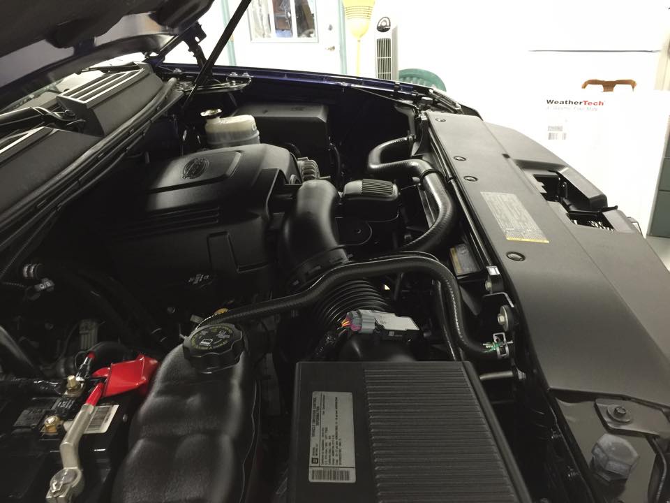 A close up of a car engine with the hood open