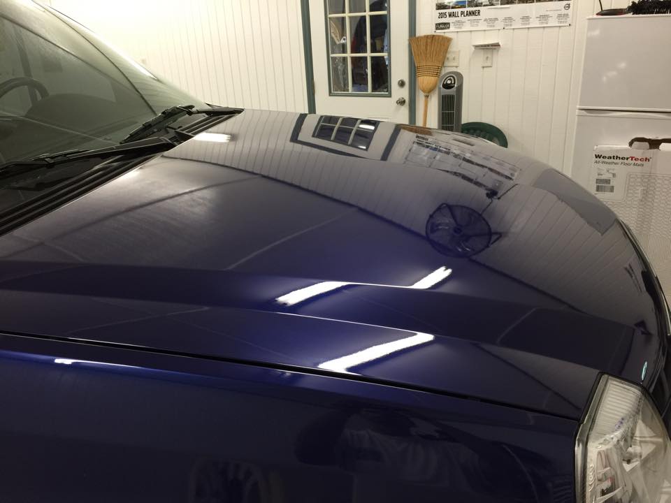 A close up of a blue car 's hood in a garage