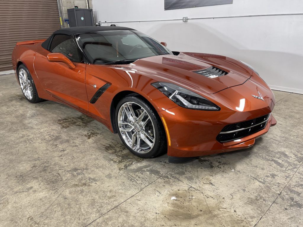 A red corvette convertible is parked in a garage.