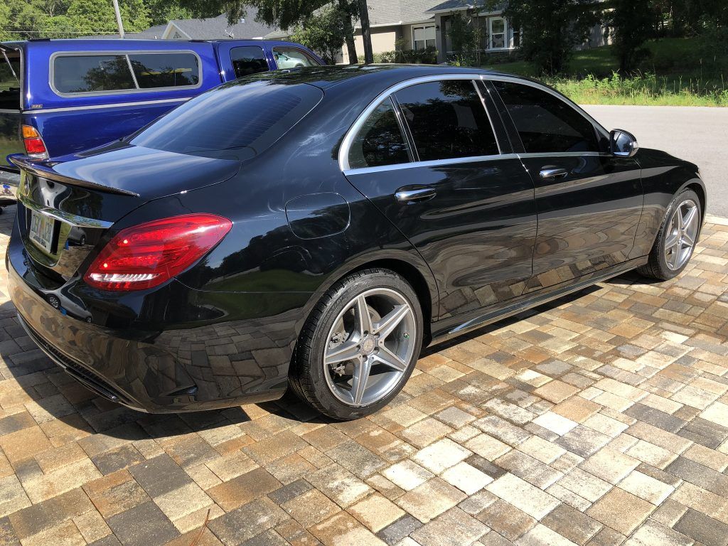 A black mercedes benz c class is parked on a brick driveway.