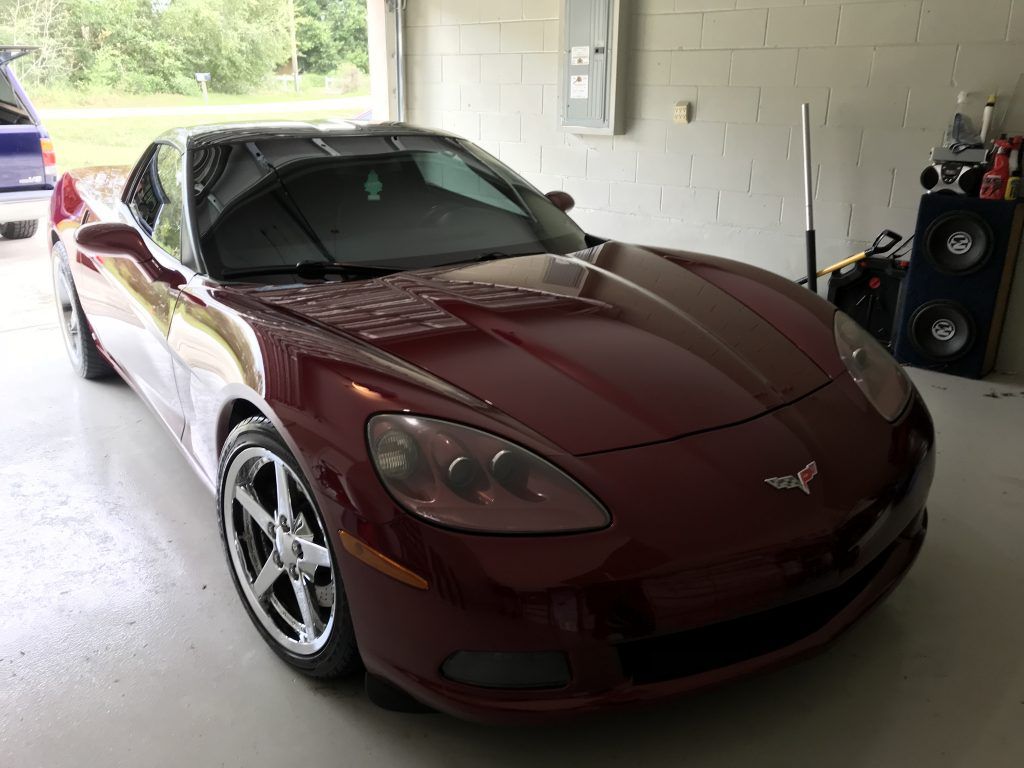 A red corvette is parked in a garage.