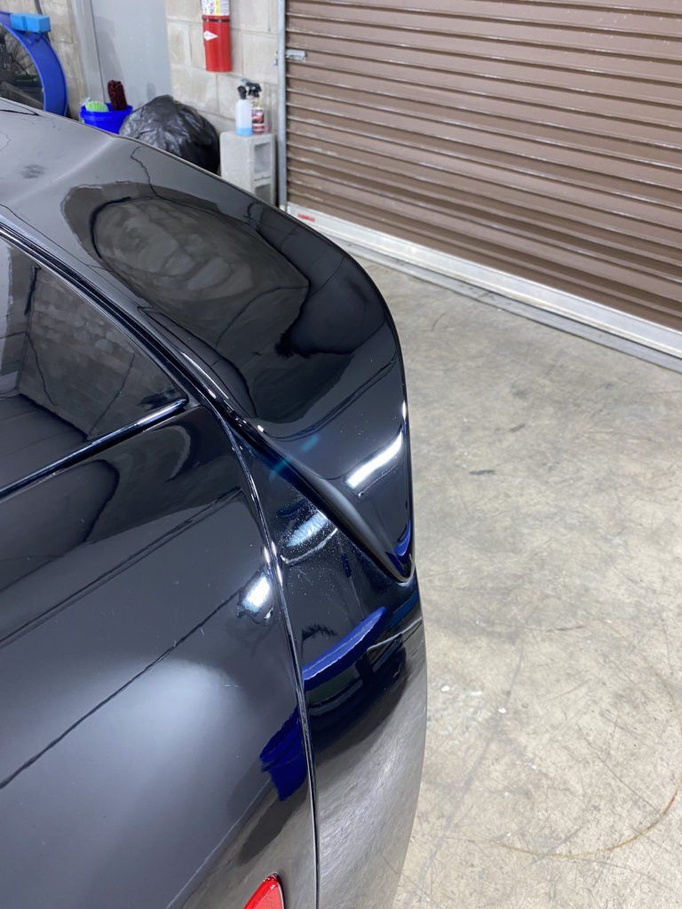 A black car is parked in a garage next to a garage door.