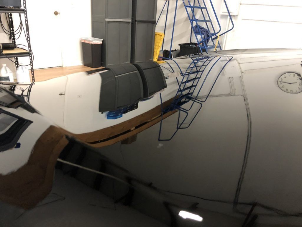 A boat is sitting in a garage next to a clock.