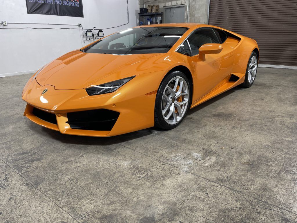 An orange lamborghini huracan is parked in a garage.