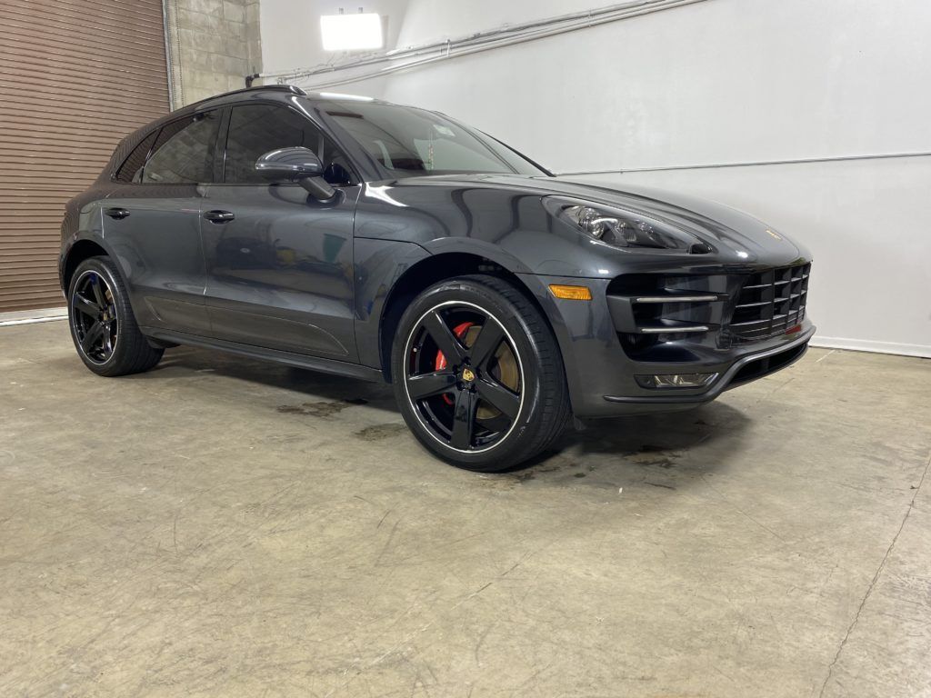 A black porsche macan turbo is parked in a garage.