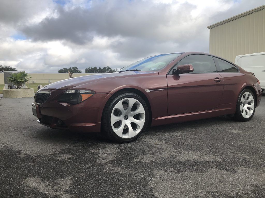 A maroon bmw 6 series coupe is parked in a parking lot.